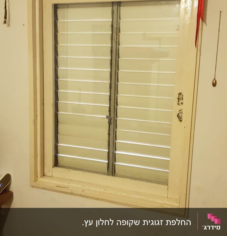 חלון עם תריסים סגורים במסגרת עץ